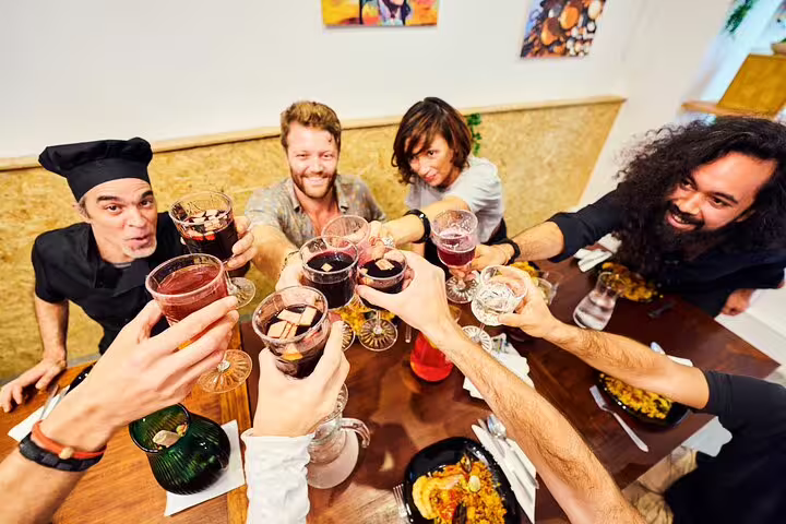 Group enjoying a toast during an engaging paella cooking class, showcasing delicious Spanish cuisine and culinary camaraderie.