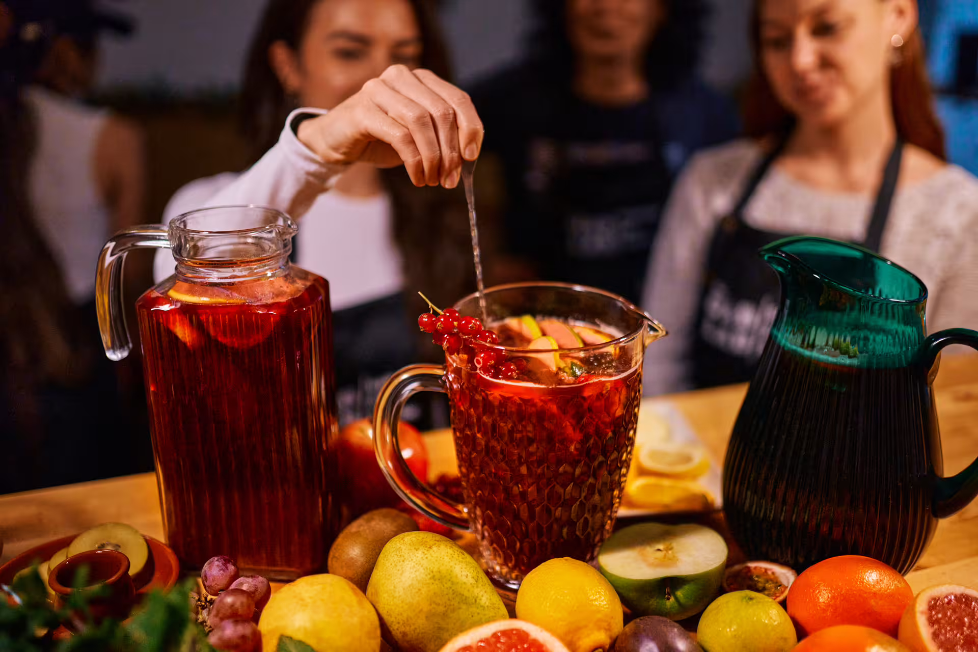 Participants enjoy vibrant sangria preparation in the Ultimate Paella Cooking Class, surrounded by fresh fruits and lively ambiance.