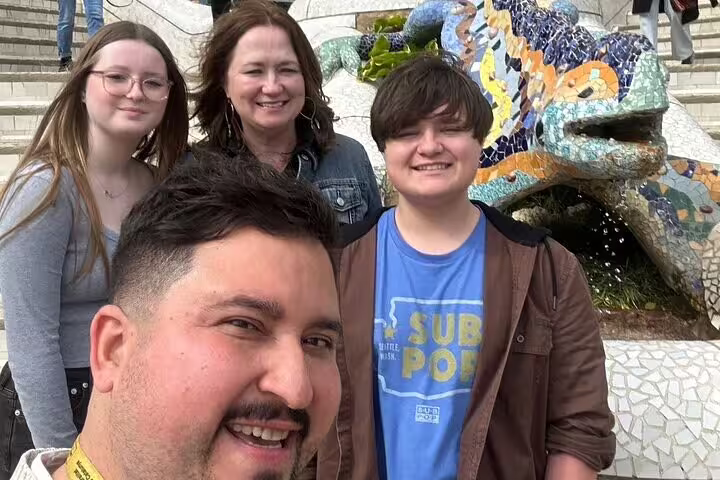 Visitors posing with the iconic mosaic dragon sculpture in Park Güell during a semi-private Barcelona tour.