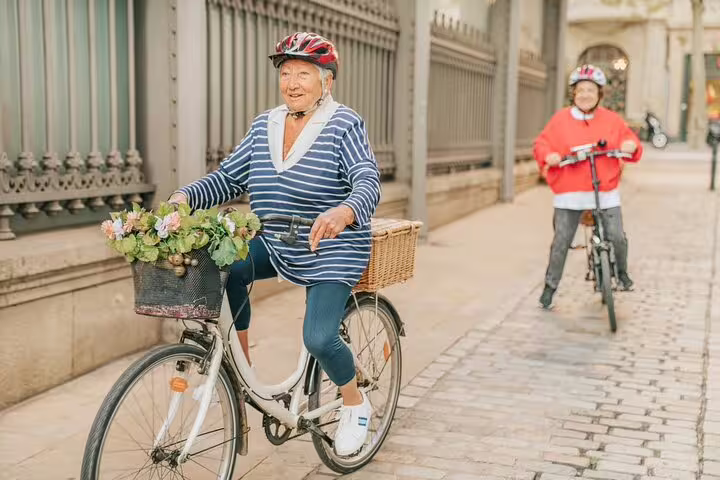 Two smiling cyclists enjoy a private bike tour in Barcelona, exploring scenic streets with Sagrada Familia tickets included.