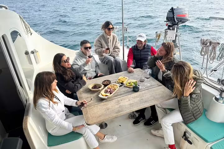 Group enjoying snacks and cava on a private catamaran in Barcelona, offering a relaxing sunset cruise experience.