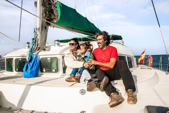 Family enjoying a private catamaran tour with snacks and cava, capturing a sunny day on the sea near Barcelona.