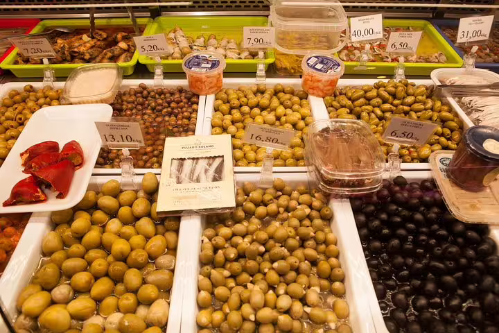 Assorted olives and pickles at a vibrant market stall in Barcelona's Raval Quarter, highlighting local culinary delights.