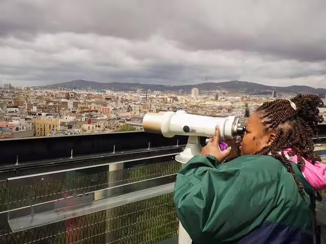 Visitor enjoys panoramic view of Barcelona's Raval Quarter through a telescope on a private walking tour under cloudy skies.