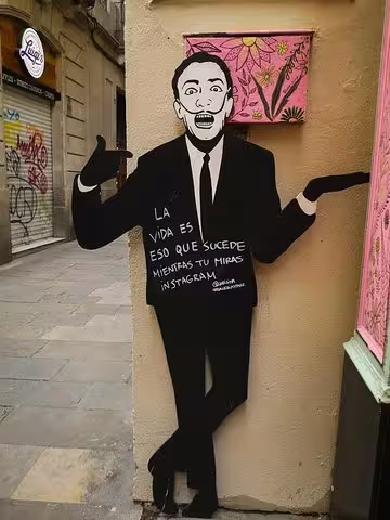 Street art in Barcelona's Raval Quarter featuring a whimsical cutout with a thought-provoking message, perfect for a cultural walking tour.