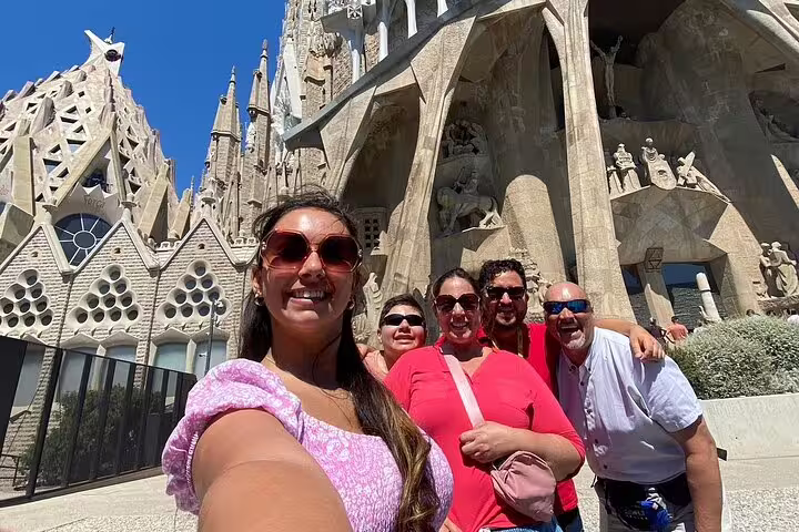 Tourists enjoying a sunny day in front of Barcelona's iconic Sagrada Familia during a city tour.