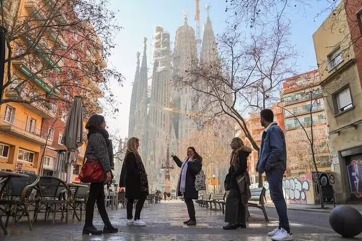 Small group listening to guide near Sagrada Familia, enjoying insider stories and skip-the-line access on a walking tour