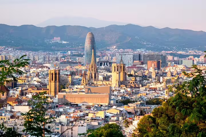 Panoramic view of Barcelona cityscape featuring Sagrada Familia and Torre Glòries against a mountainous backdrop.