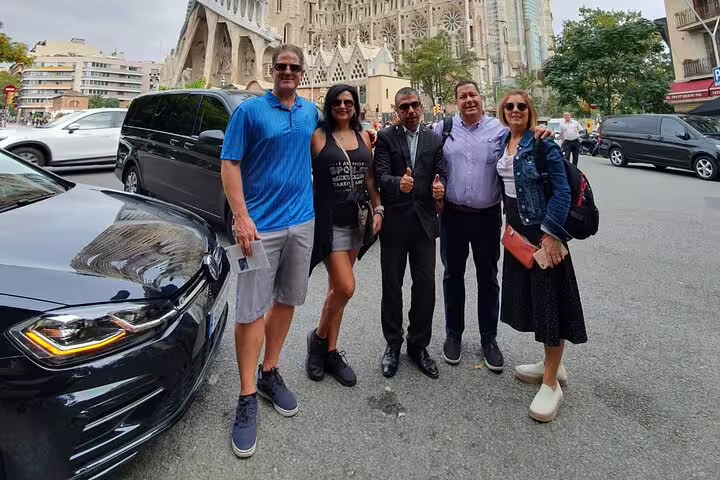 Tourists enjoying a Barcelona tour with a guide in front of the iconic Sagrada Familia.