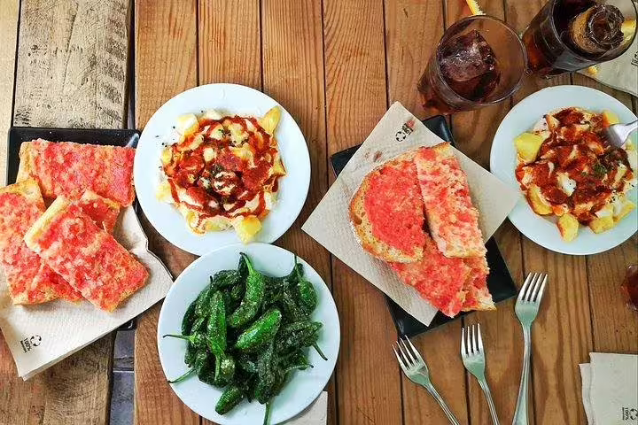 Assorted Spanish tapas including tomato bread and peppers, highlighting the culinary delights of a Barcelona food tour.