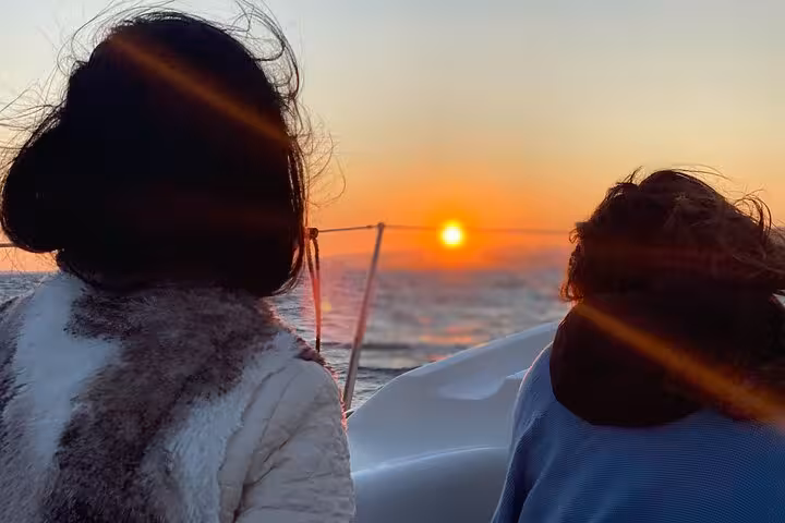 Couple watching the Barcelona sunset from a private sailboat cruise with live saxophone and open bar