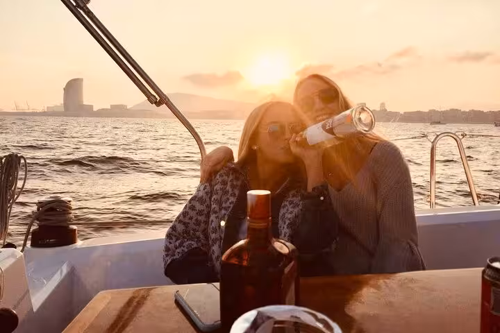 Friends toast with drinks on a Barcelona sunset private sailing tour with open bar, skyline views and sea breeze