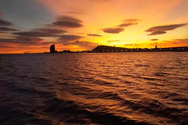 Barcelona sunset private sailing tour with open bar and snacks, golden sky over Mediterranean coastline