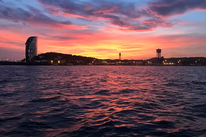 Barcelona sunset cruise by sailboat with open bar and snacks, W Hotel and harbor skyline at dusk