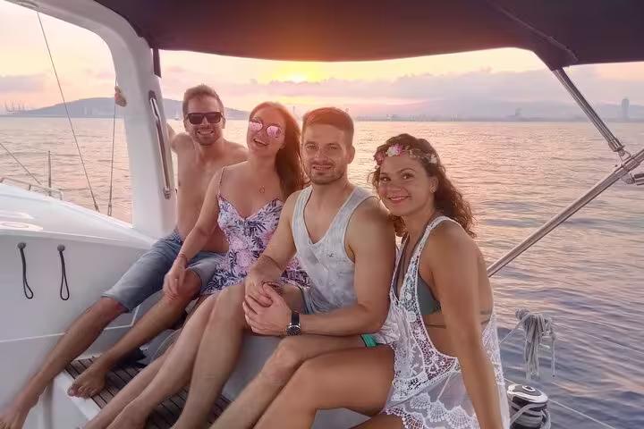 Friends relaxing on a Barcelona sunset sailing tour with open bar and snacks, enjoying golden hour at sea