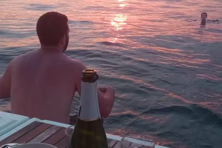 Guests swim at sunset off a sailboat in Barcelona with open bar cava and snacks on deck