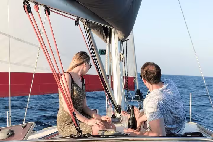 Couple enjoying a private sunset sailing experience with drinks on a yacht in Barcelona, gazing at the serene Mediterranean Sea.