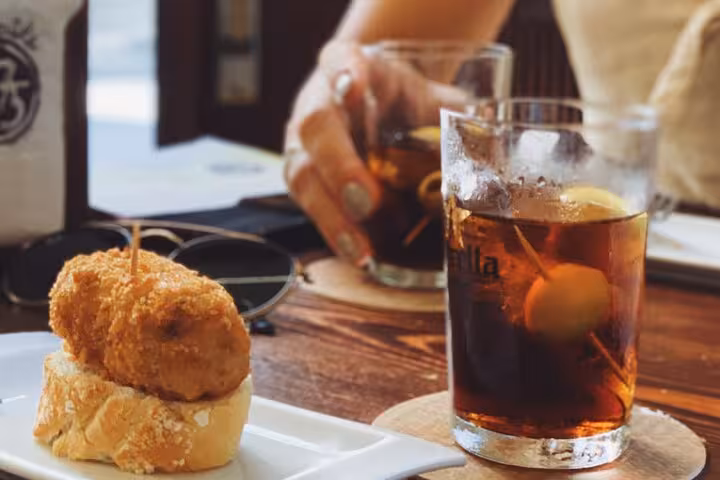 Vermouth and croquette pintxo on a wooden table, classic Barcelona tapas and wine tasting tour stop
