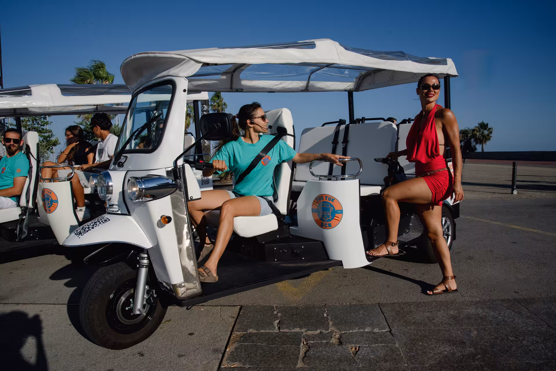 Barcelona tuk tuk tour pickup by the beach, open-air ride with driver and guests on the seafront