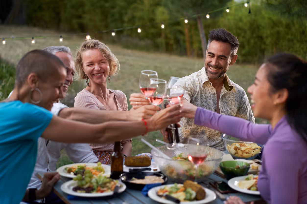 Friends toasting rosé at an outdoor winery meal on a half-day vineyard and wine tasting tour from Barcelona