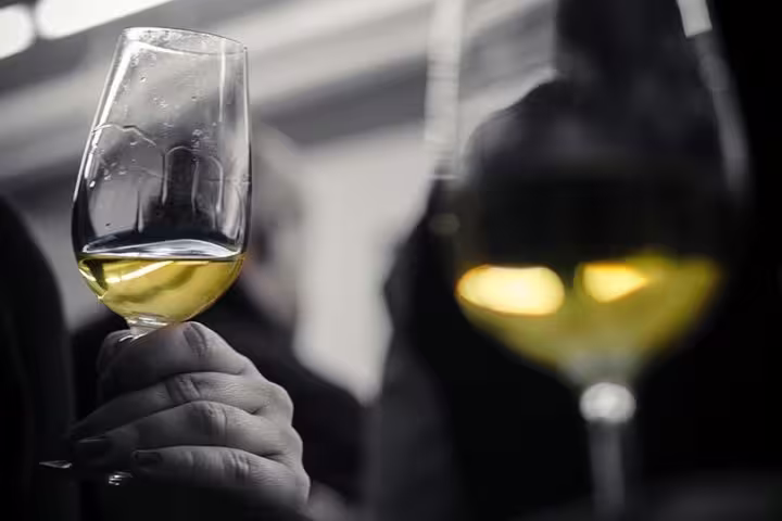 Close-up of a hand holding a glass of white wine during a tasting session, highlighting Barcelona's wine culture.