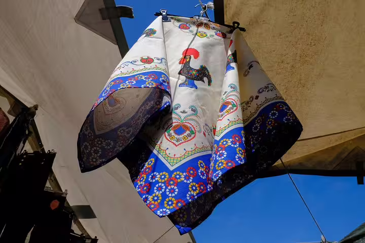 Colorful Barcelos rooster cloths sway in the market, offering a glimpse of local culture on the Porto private tour.