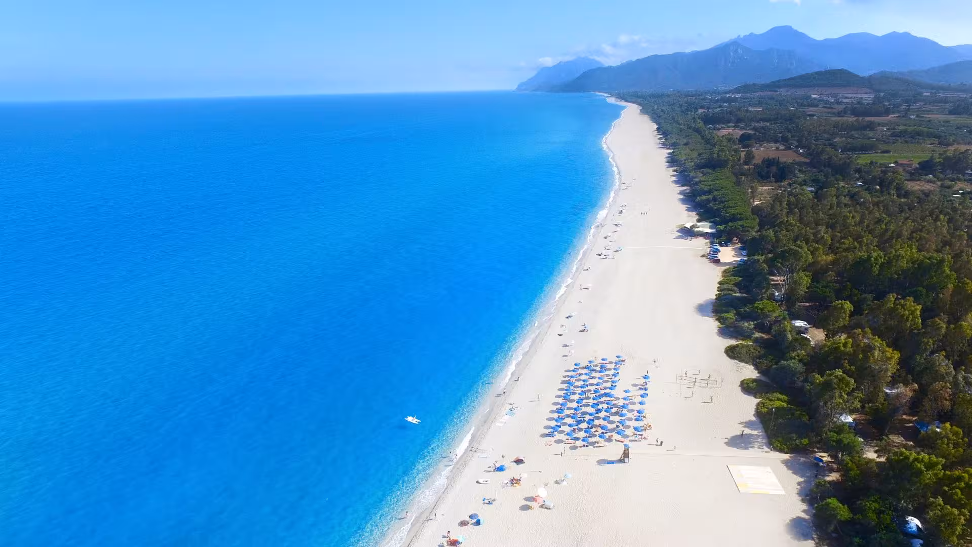 Aerial view of Bari Sardo's pristine beach, showcasing turquoise waters and a long stretch of sandy shore.