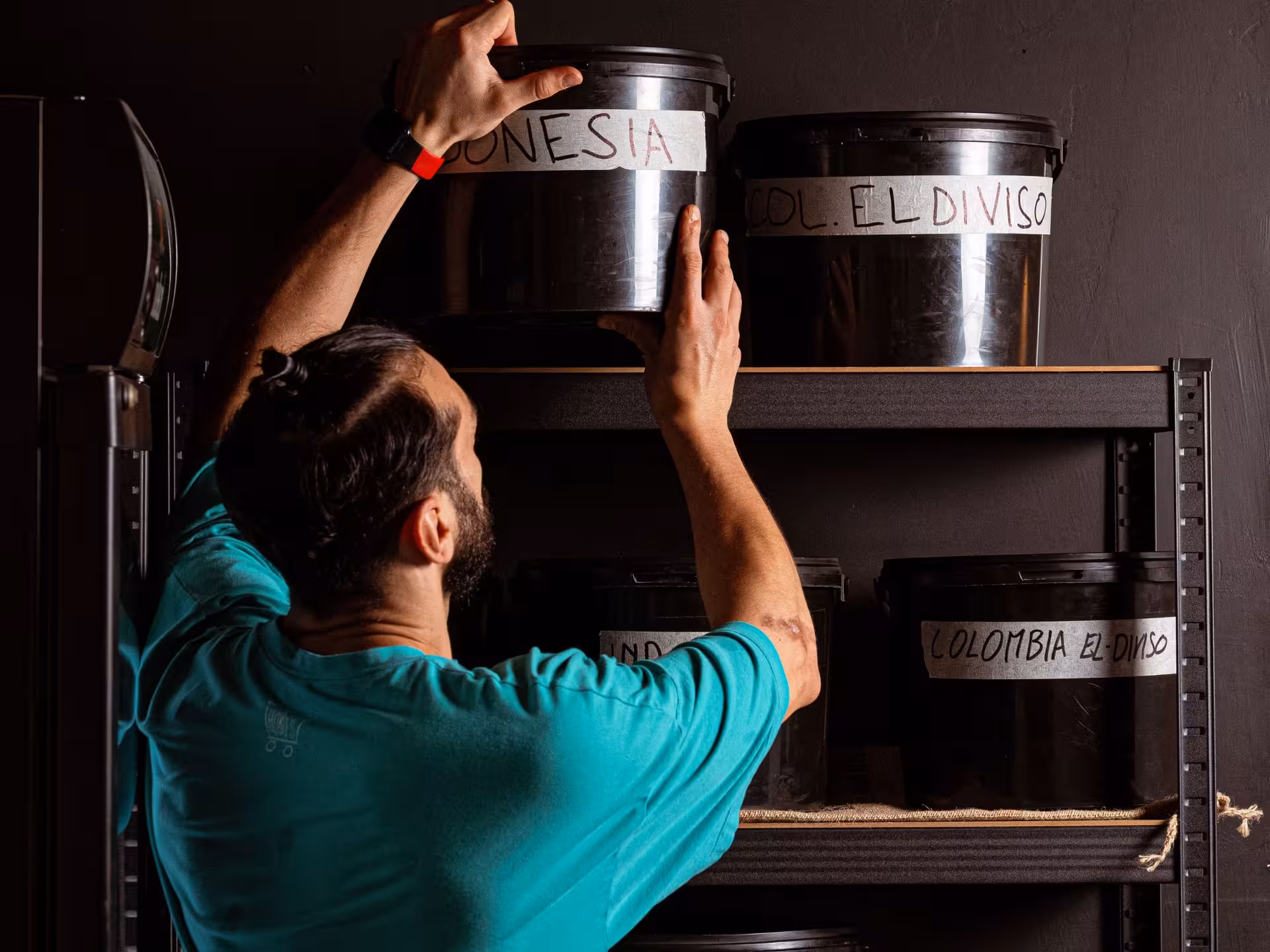 Barista organizing labeled coffee containers on a shelf during a tasting experience in Rome.