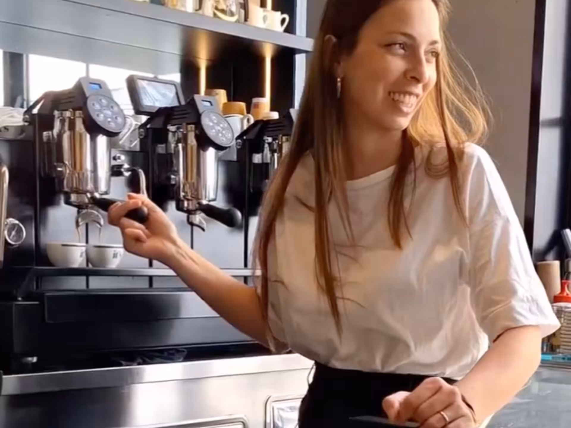 Barista smiling while preparing espresso at a modern coffee machine during a Neapolitan coffee experience.
