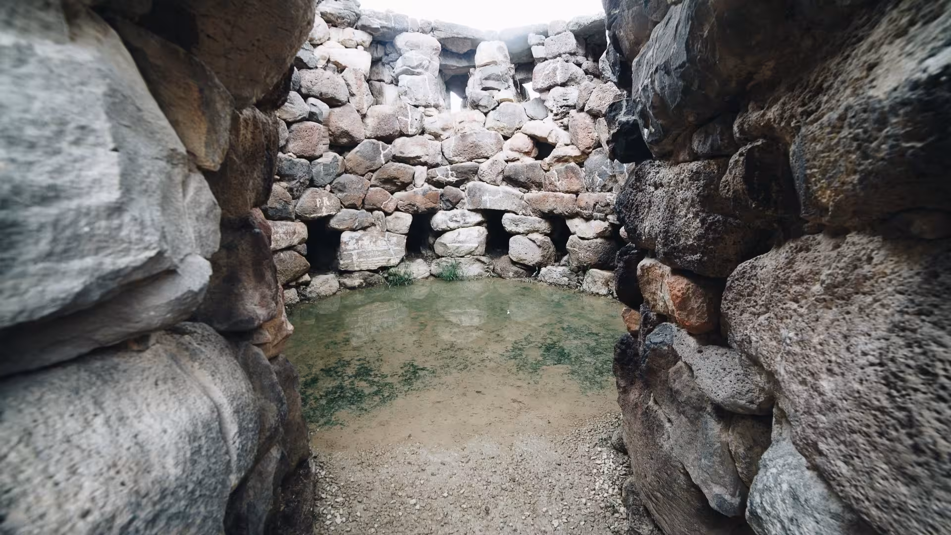 View the ancient stone chamber with water features at Barumini, showcasing unique Nuragic architecture in Sardinia.
