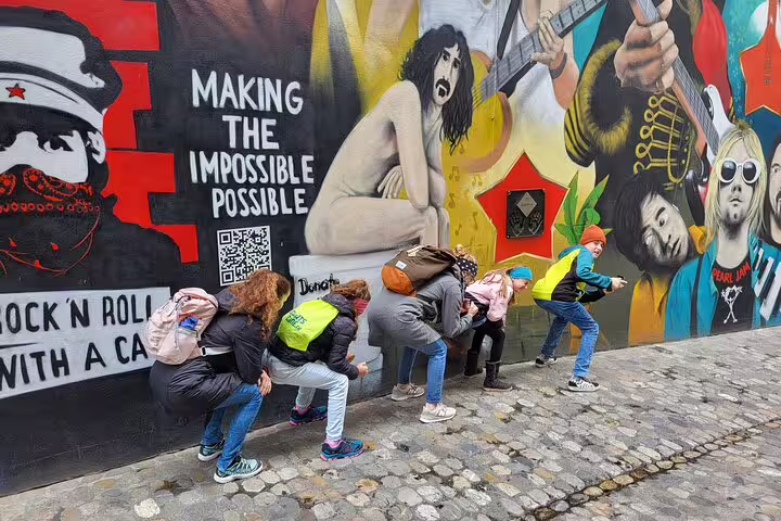 Kids crouch by Basel street art mural during a self-guided scavenger hunt tour through city sights