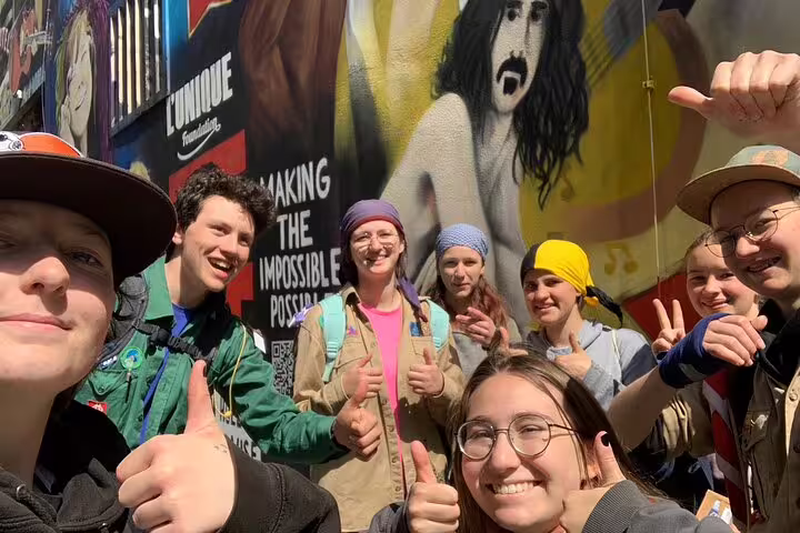 Group selfie with thumbs up at Basel mural stop during a self-guided scavenger hunt and city sights tour