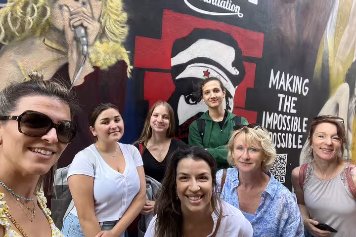 Friends pose by colorful street art in Basel on a self-guided scavenger hunt tour with QR code clues