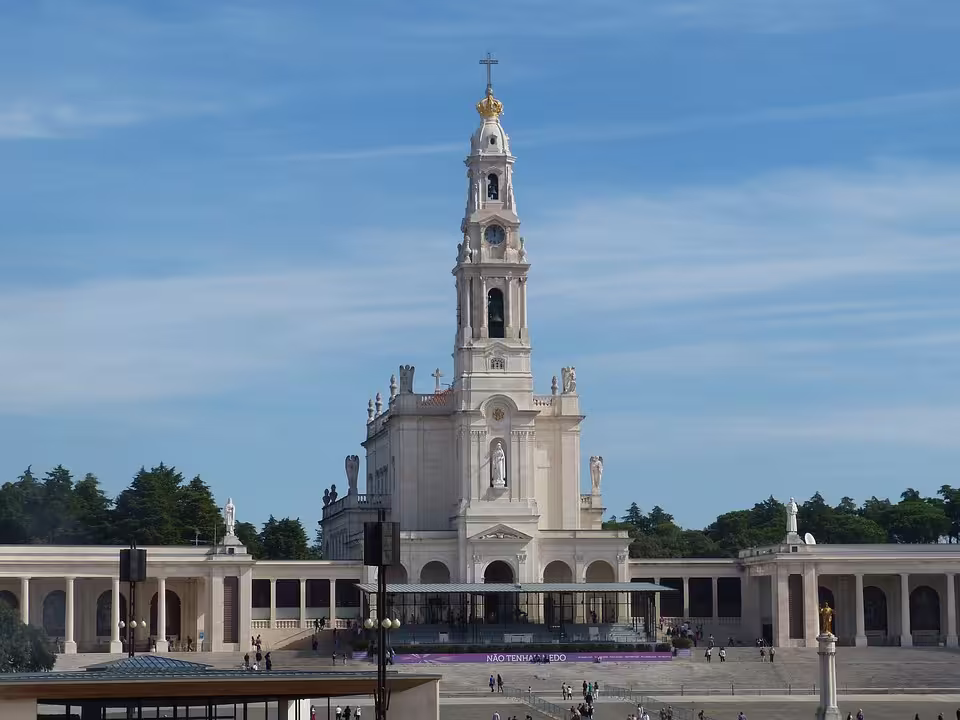 The majestic Basilica of Our Lady of the Rosary in Fátima stands under a clear blue sky, a centerpiece of religious pilgrimage.
