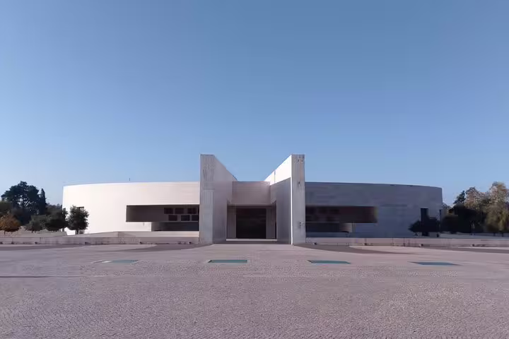 Modern facade of the Basilica of the Holy Trinity in Fatima, showcasing its sleek, contemporary design under a clear sky.