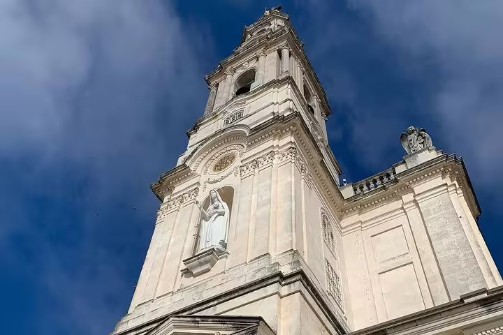 Stunning view of the Basilica of Our Lady of the Rosary in Fátima, highlighting architectural details under a blue sky.
