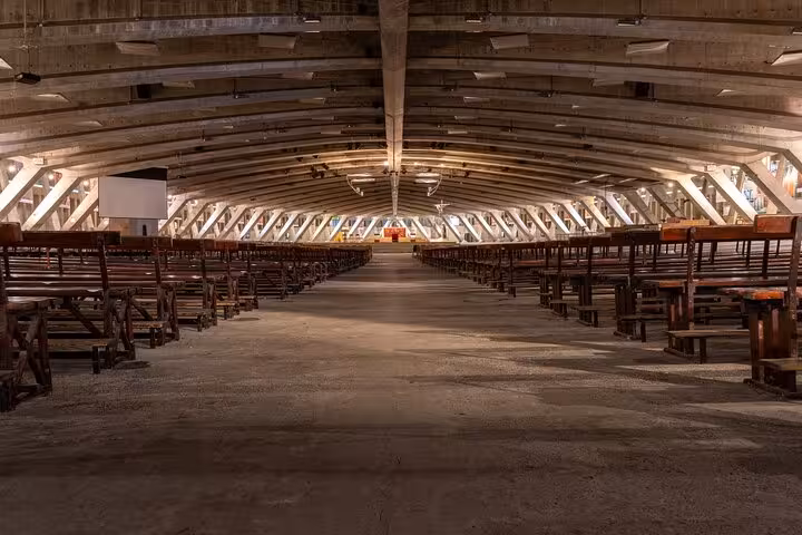 Spacious interior of the modern Basilica of St. Pius X in Lourdes, showcasing its unique architectural design.