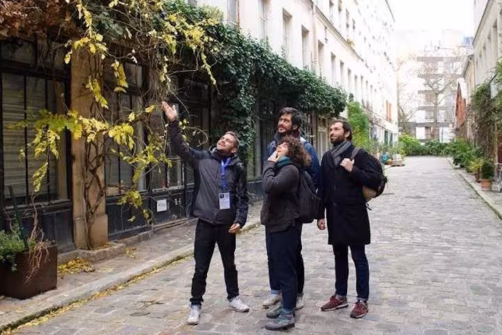Tour group exploring a charming, ivy-clad Parisian alley on the Bastille & Paris Best Market Food Tour.