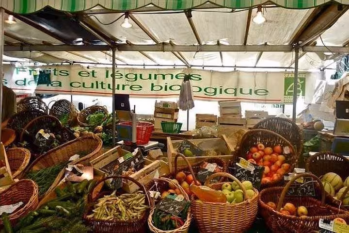Explore organic fruits and vegetables at a bustling Bastille market stall during the Paris Best Market Food Tour.