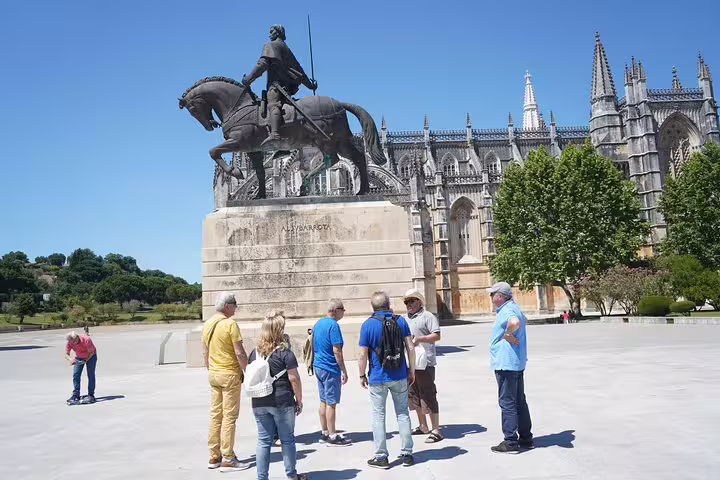 Tourists admire the equestrian statue and stunning architecture at Batalha Monastery during a private full-day tour from Lisbon.