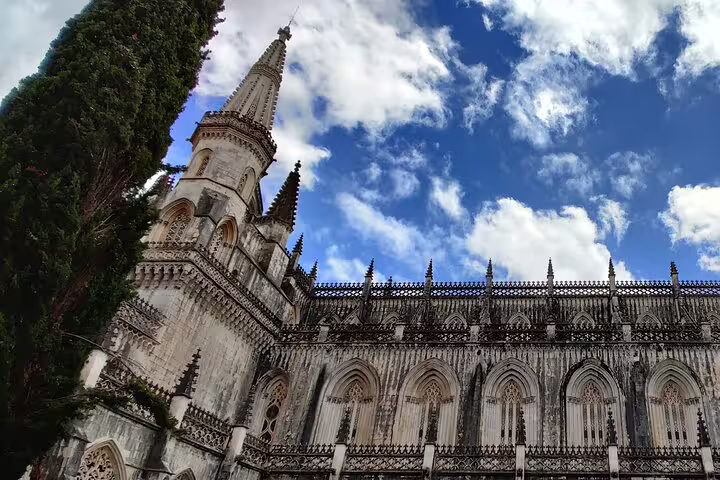 Gothic architecture of the Batalha Monastery under a vibrant sky, featured on a private day tour to Fatima, Nazaré, and Obidos.
