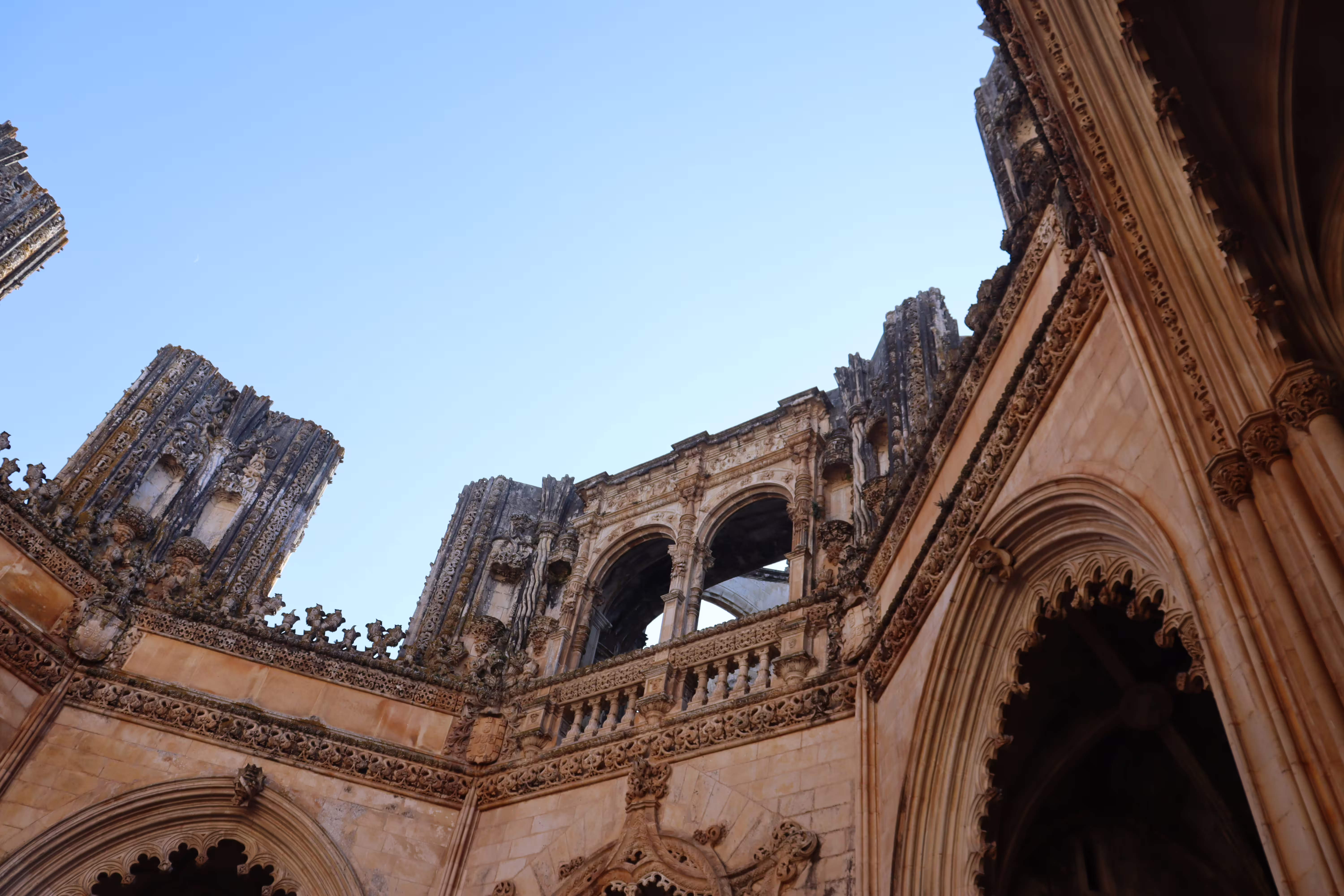 Ornate Gothic architecture of Batalha Monastery under a clear blue sky, featured on a private tour through Tomar, Fátima, and Batalha.