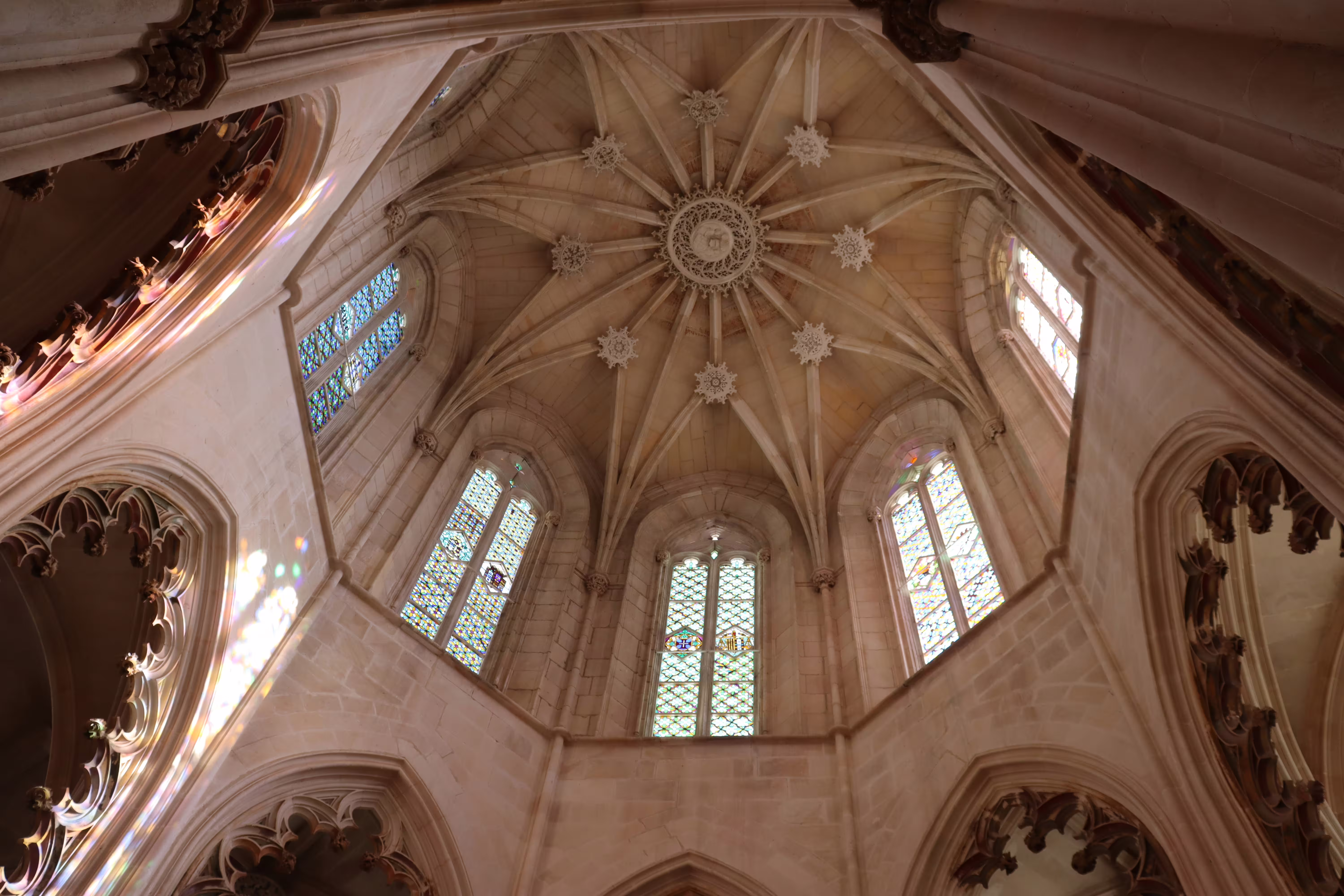 Intricate Gothic ceiling and stained glass windows inside Batalha Monastery, featured in private Tomar, Fátima, Batalha tour.