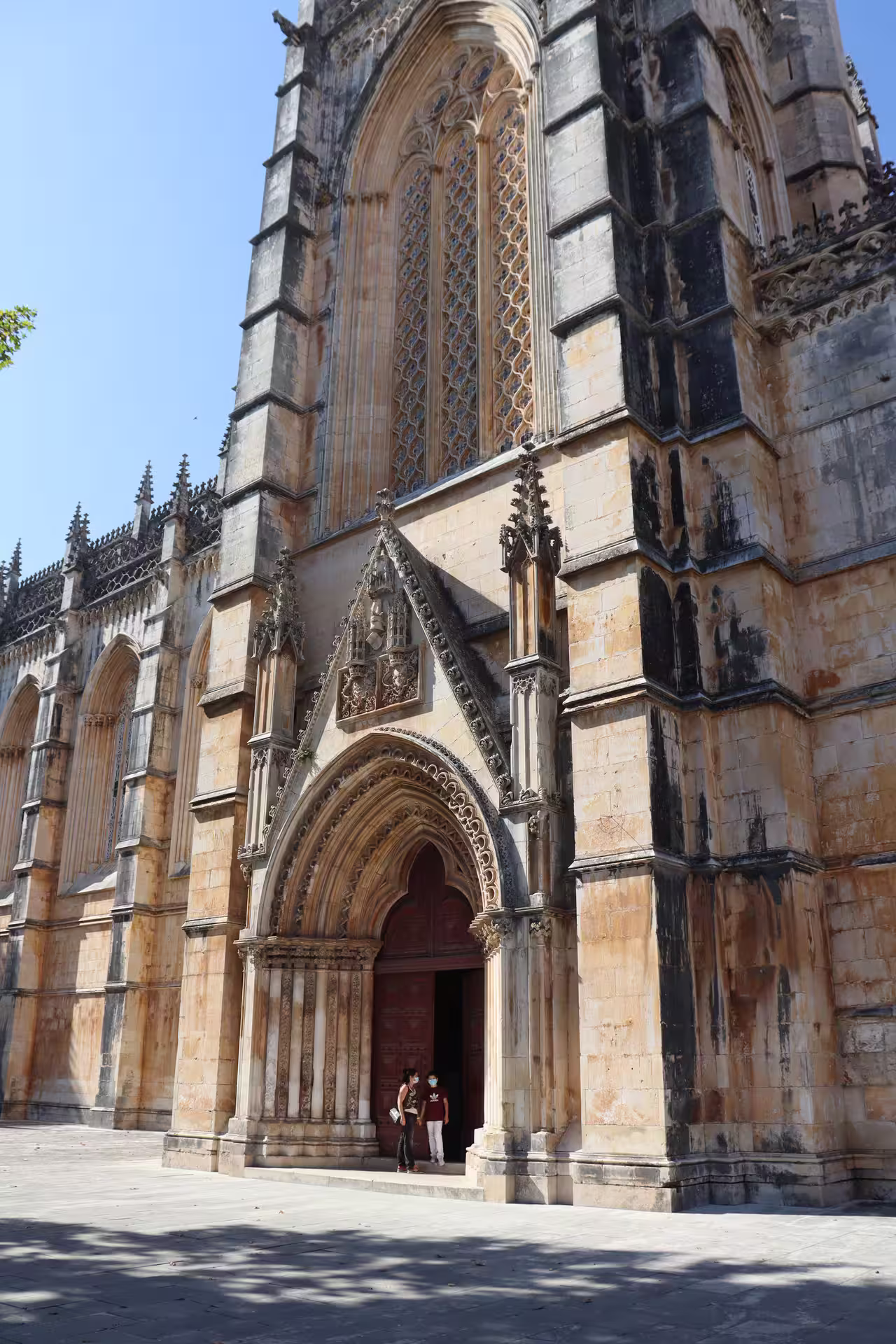 Gothic architecture of Batalha Monastery's ornate entrance on a sunny day, featured in a private tour of Tomar, Fátima, and Batalha.
