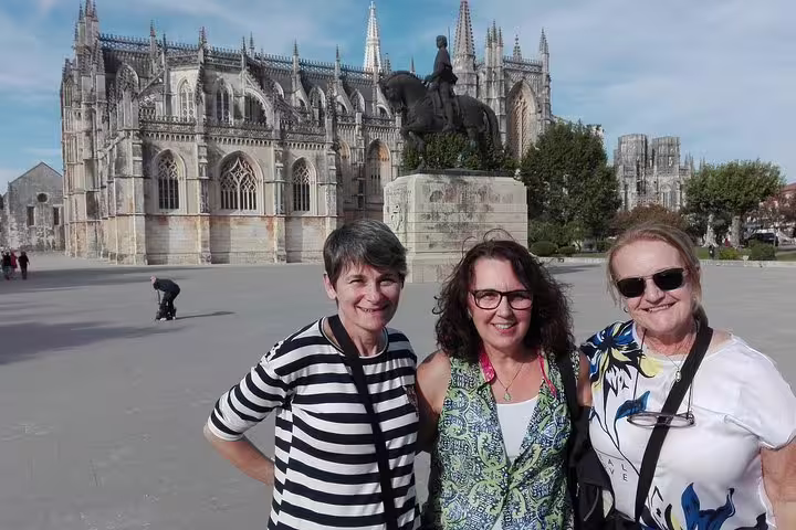 Tourists enjoy a sunny day at the historic Batalha Monastery during a private full-day tour from Lisbon, exploring Óbidos, Nazaré, Alcobaça, and Fátima.