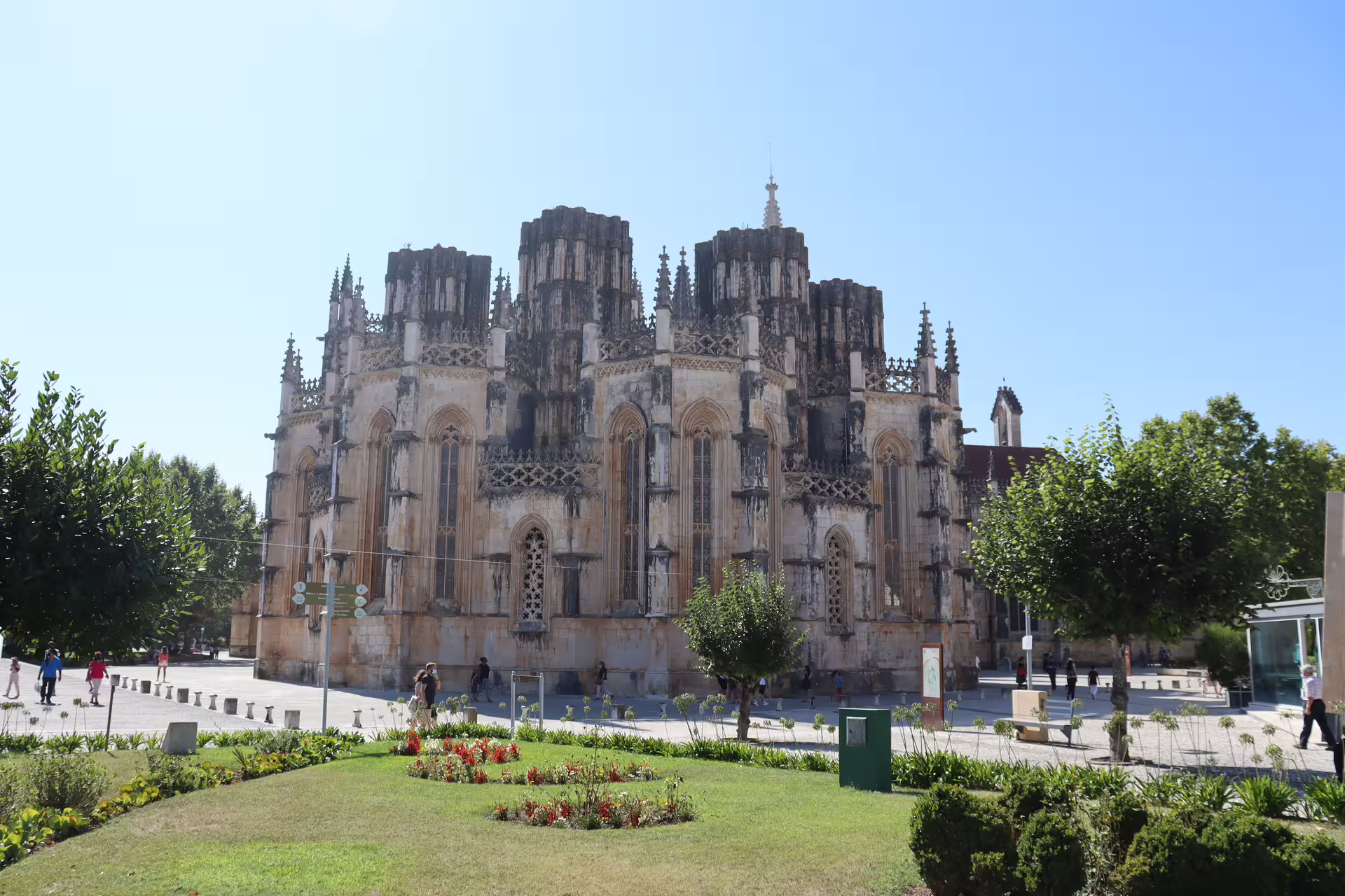 Historic Batalha Monastery facade surrounded by lush gardens under clear blue skies on private tour of Tomar, Fátima, and Batalha.