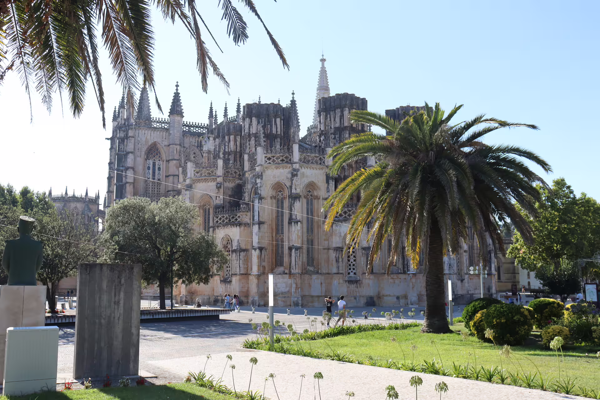 Batalha Monastery with palm trees in the foreground, featured on a private tour through Tomar, Fátima, and Batalha historical sites.