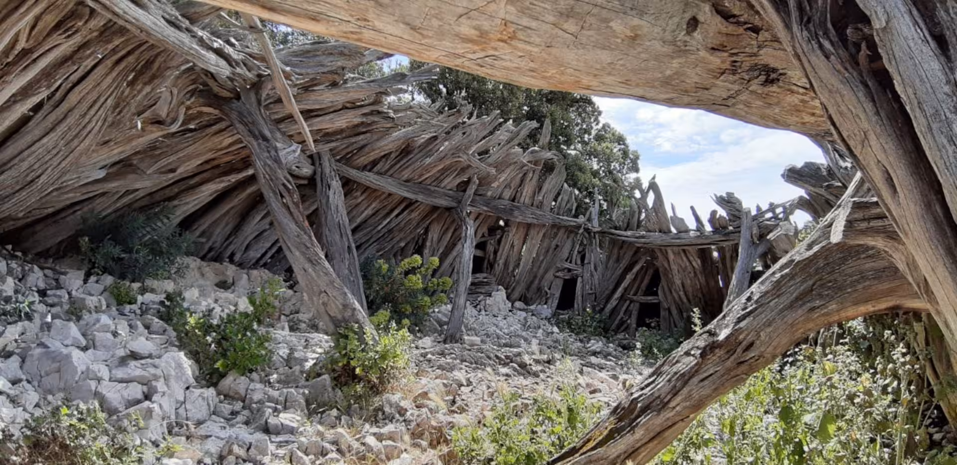 Rustic wooden shelter amidst rocky terrain on the Baunei trekking route to Cala Mariolu, Sardinia.