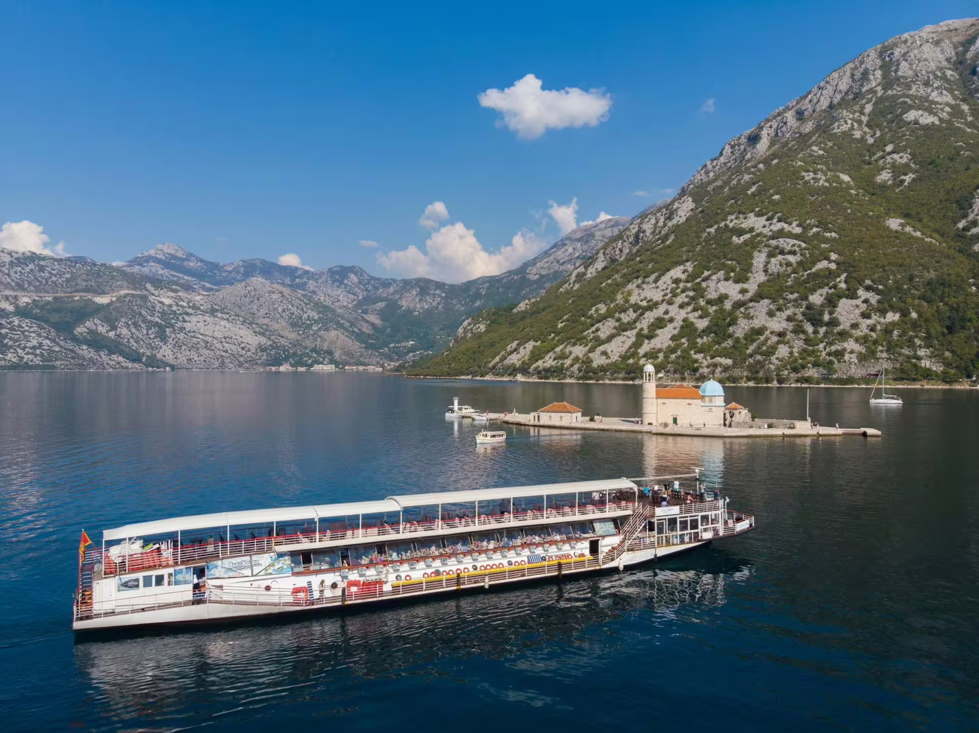 Cruise boat sailing Bay of Kotor toward Our Lady of the Rocks, Montenegro, on a day trip from Dubrovnik