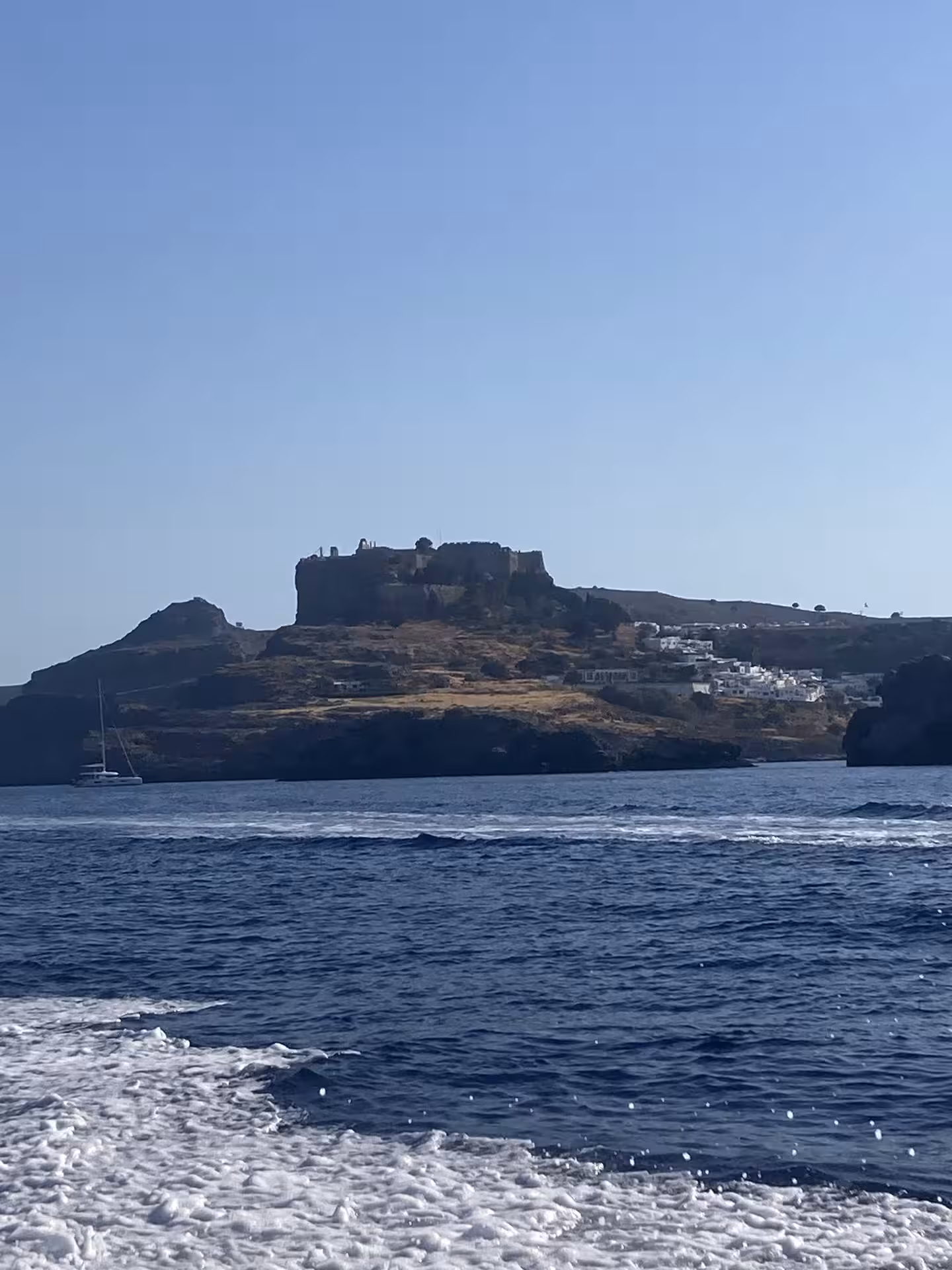Coastal cliffs and island fortress seen from Bayliner M17 on a 2-hour cave and snorkelling boat tour across blue sea